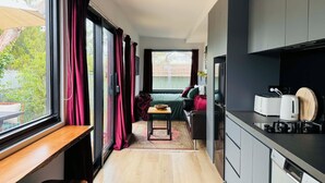 Una cocina moderna con lavavajillas integrado, un comedor con mesa y sillas, y vistas al exterior a través de amplios ventanales.