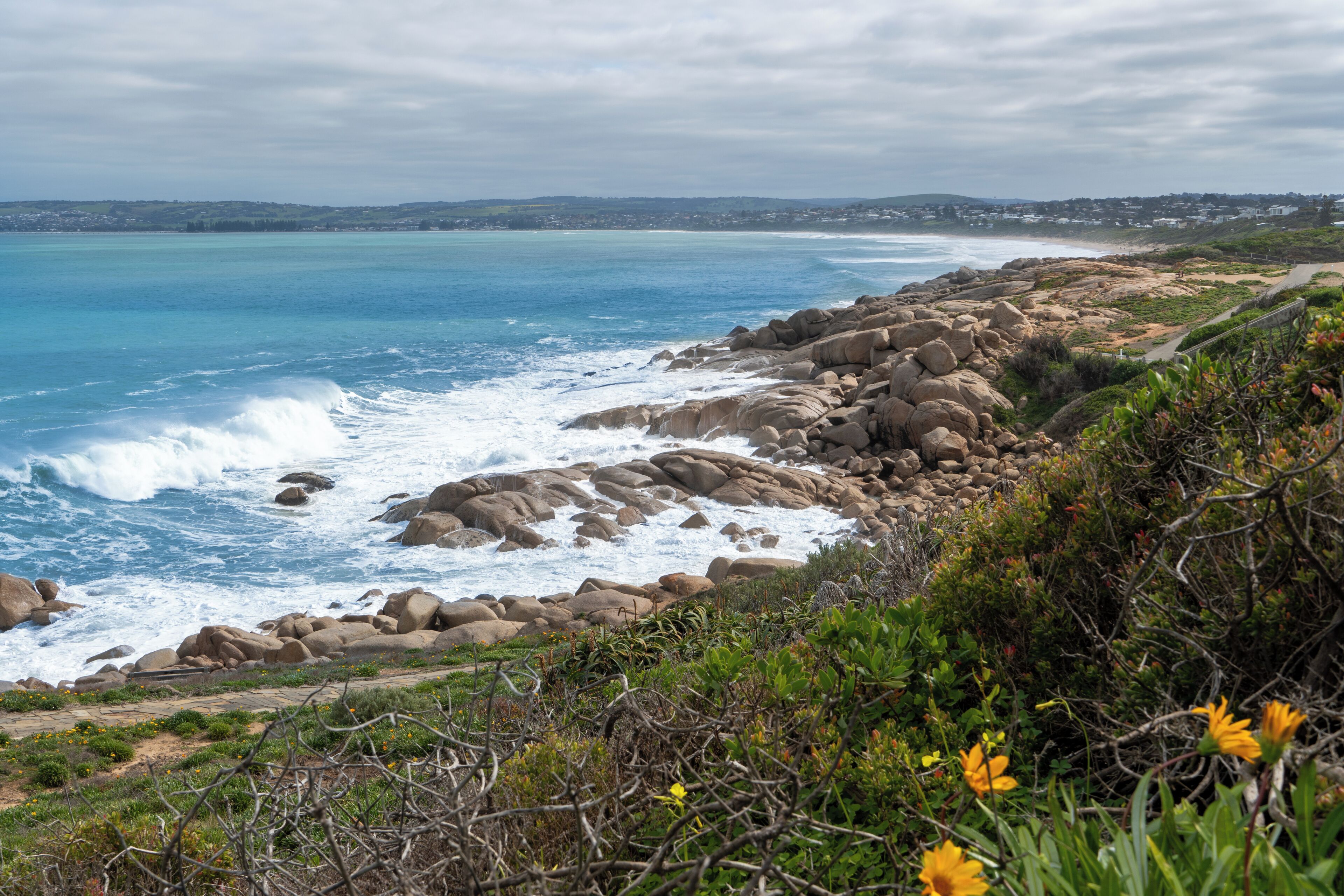 A coastal landscape with rocky terrain, a beach, and a distant town.