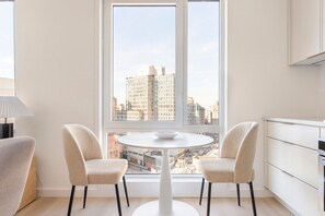 A modern kitchen with white cabinets, a round dining table, and two chairs. - Blueground | Downtown Brooklyn, rooftop, nr Brooklyn Bridge (New York)