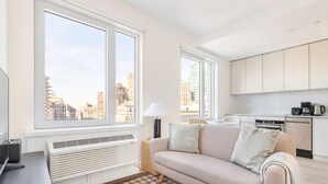 A modern apartment with a sofa, a lamp, a checkered rug, and a kitchen area. - Blueground | Downtown Brooklyn, rooftop, nr Brooklyn Bridge (New York)