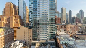 Un immeuble de grande hauteur doté d’une façade moderne en verre, entouré de bâtiments plus anciens en briques.