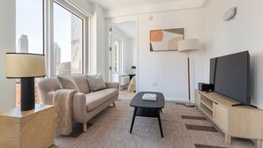 Un salon moderne avec un canapé, une table basse, un téléviseur et une lampe.