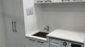 A kitchen with a built-in dishwasher, a sink, and cabinets. - Bellevue overlooking the ocean (Manyana)