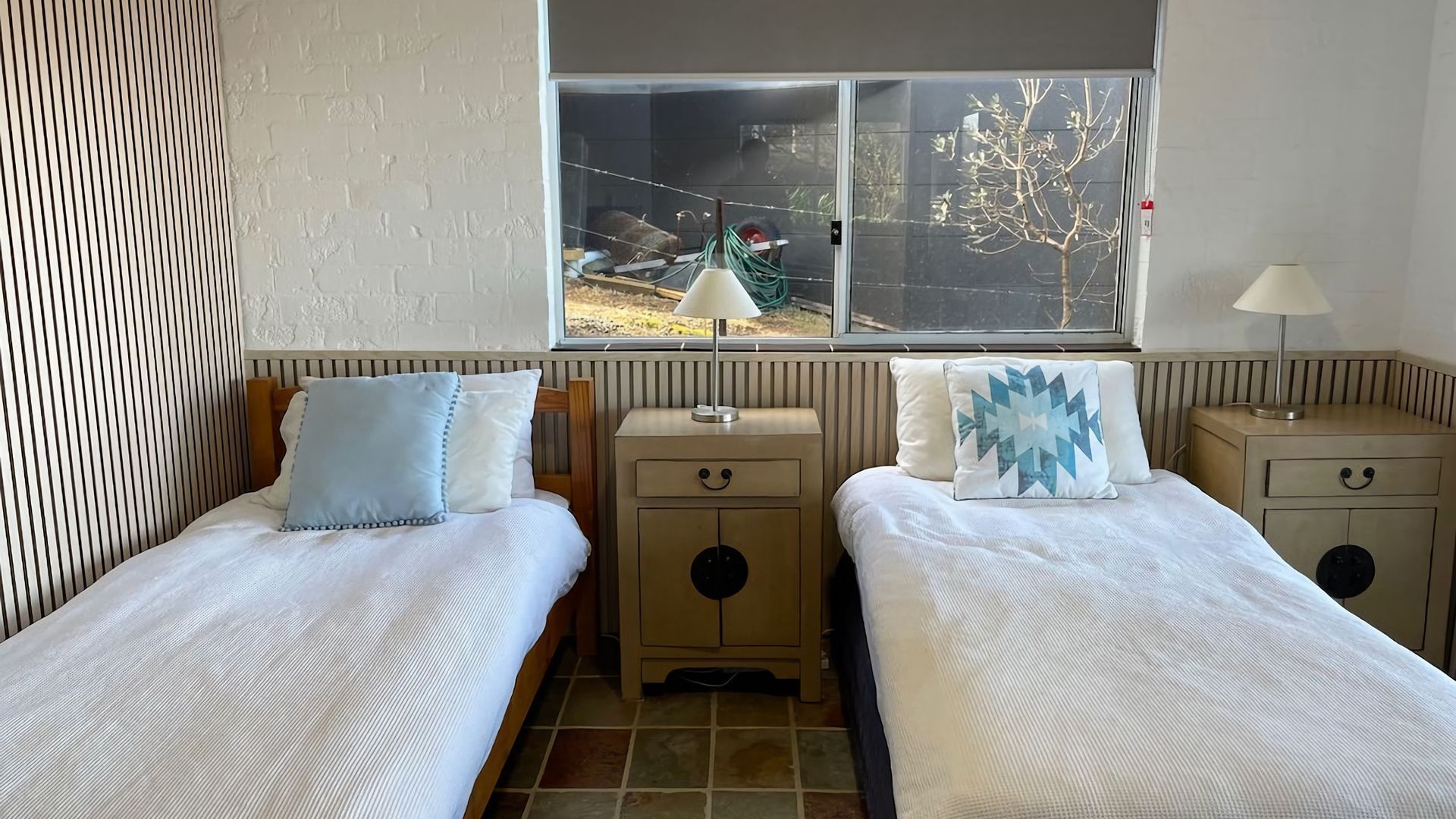 Une chambre avec deux lits simples, une fenêtre donnant sur un arbre et un radiateur.