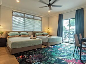 Ein Hotelzimmer mit zwei Betten, einem Deckenventilator, einem großen Fenster mit Jalousien, einem Balkon mit Blick und einem Teppich mit Blumenmuster.