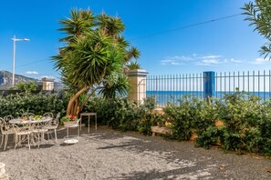 Un espace extérieur aménagé avec des tables et des chaises, un palmier et une vue sur la mer.