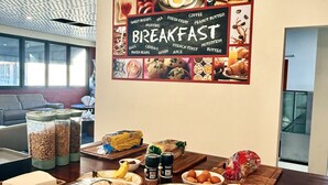A breakfast buffet with various food items and a wall sign listing breakfast options. - Gallery Boutique Hotel (Bibra Lake)