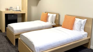 Una habitación de hotel con dos camas individuales, un escritorio y un minibar.