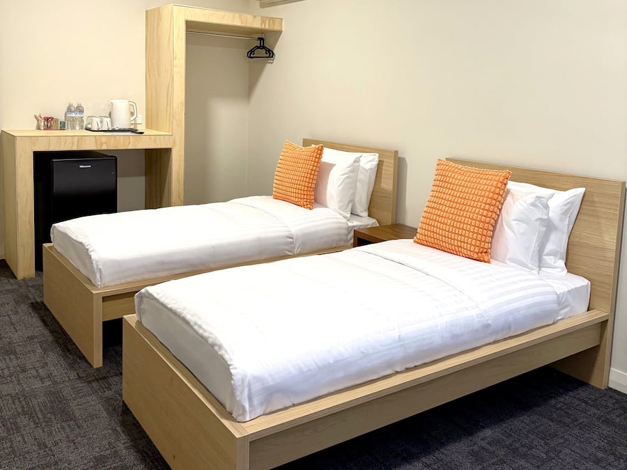 Una habitación de hotel con dos camas individuales, un escritorio y un minibar.