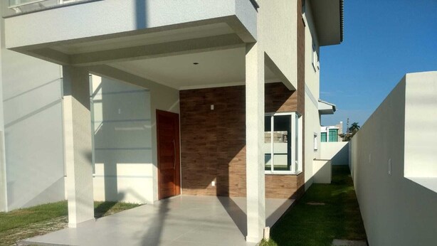Una casa moderna con un porche cubierto, una puerta de madera y un pequeño jardín.