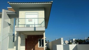 Una casa moderna de dos pisos con un balcón, un garaje y un césped bien cuidado.