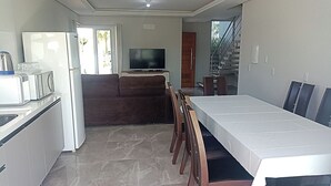 Una cocina moderna con comedor, un sofá y un televisor al fondo.