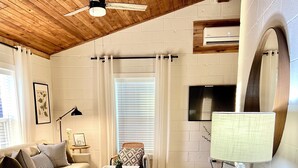 A living room with a white sofa, a coffee table, a lamp, and a TV. - The Twin Gables / Peaceful Cottage-feel 2 bedroom (Waco)