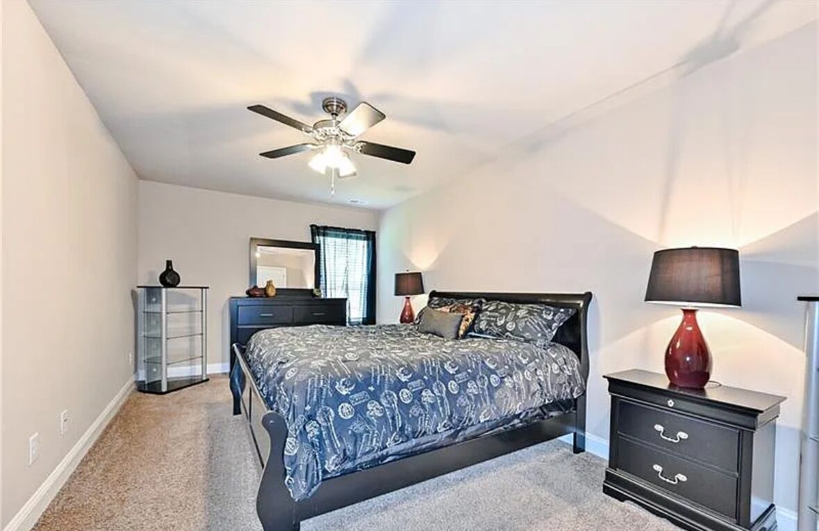Une chambre à coucher avec un lit, un ventilateur de plafond, une commode et une table de chevet.
