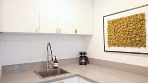 A modern kitchen with white cabinets, a stainless steel sink, and a coffee maker. - Cozy La Costa Studio Retreat (Carlsbad)