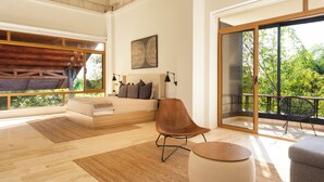 Una sala de estar moderna con un ventanal grande, un sofá, un sillón y una mesa redonda.