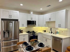 A modern kitchen with white cabinets, stainless steel appliances, and a dining area with a table set for four.