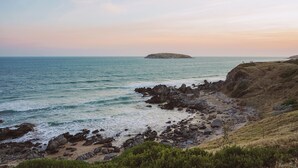 A coastal landscape with rocky terrain, a sandy beach, and a small island in the distance. - Forrest House Victor Harbor (Victor Harbor)