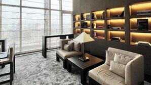 Een moderne woonkamer met een bank, salontafel en lamp. Er is een groot raam met uitzicht op de stad.
