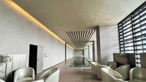 Een moderne lobby met een centraal glazen partitionering, zithoeken en een hoge plafond met lineaire verlichting.