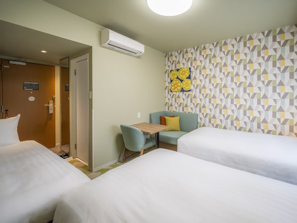 A hotel room with two beds, a small table, a chair, and a wall with a geometric pattern. - Tabino Hotel Aso Kumamoto Airport (Ozu)