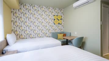 A hotel room with two beds, a small table, a sofa, and a wall with a geometric pattern.