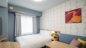 Habitación de hotel con cama, mesita de noche, lámpara y un cuadro abstracto colorido en la pared.