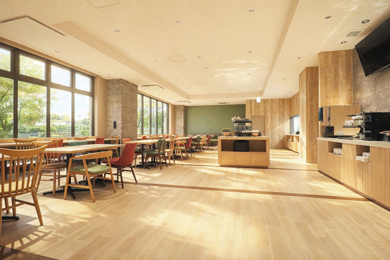 Un vaste espace dédié à la salle à manger, avec des tables et des chaises en bois, de grandes fenêtres et un comptoir de cuisine.