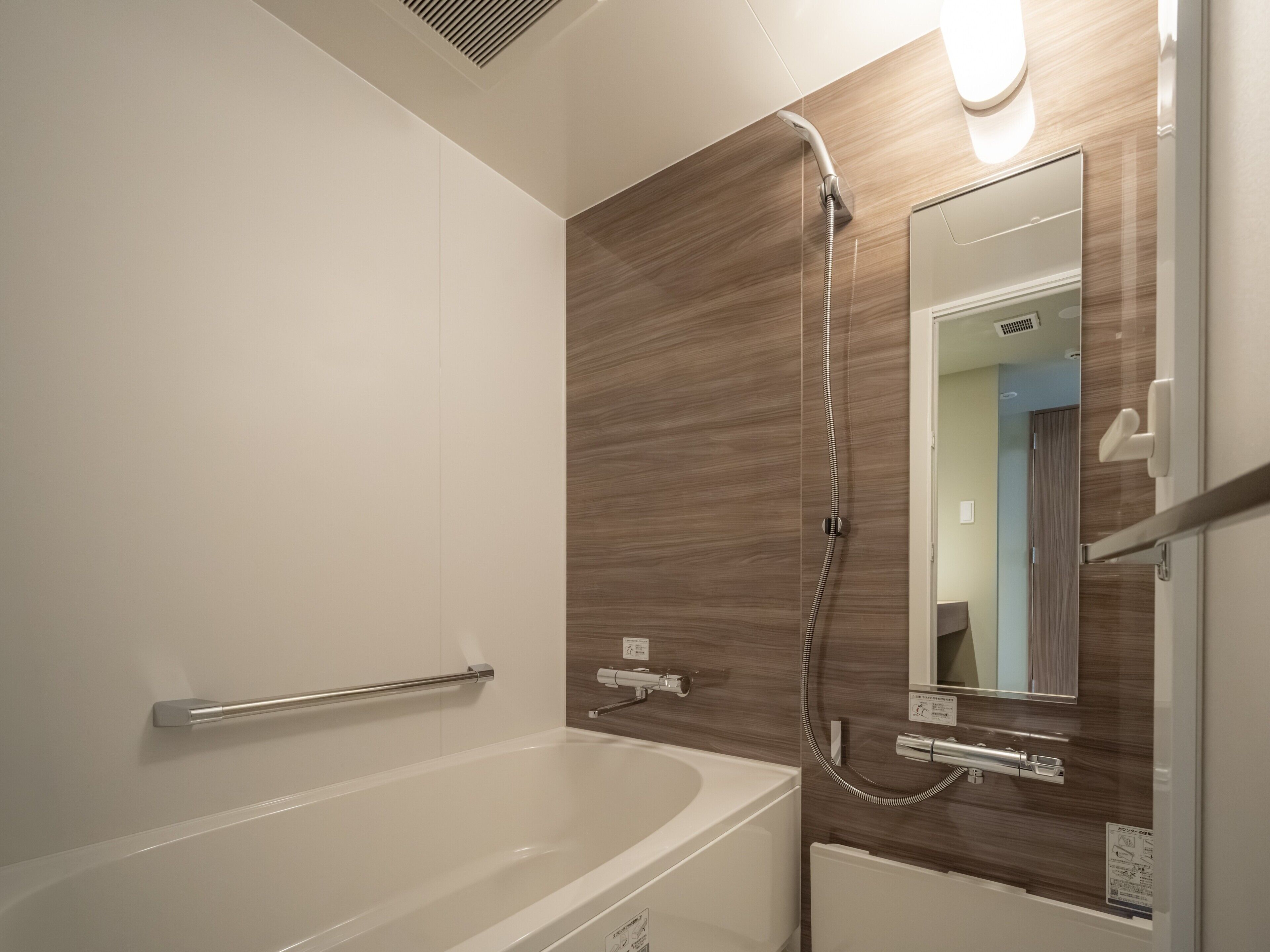Een moderne badkamer met een bad, een douche, een spiegel en een handdoekhouder.