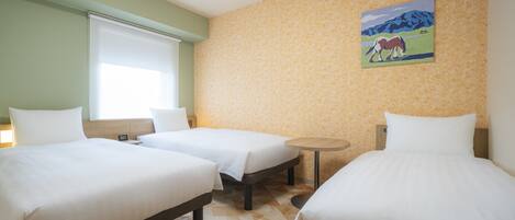 A hotel room with two beds, a small table, and a painting on the wall.