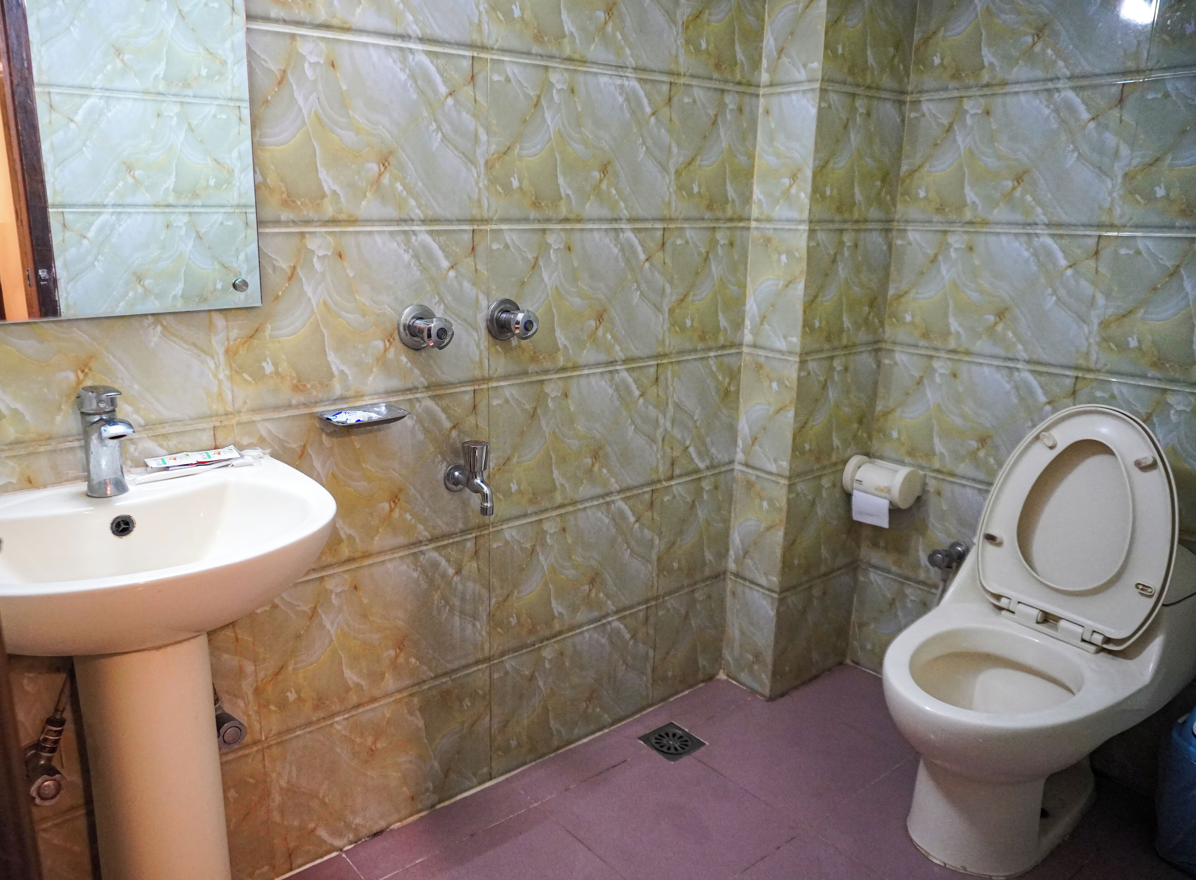 A bathroom with a sink, toilet, and a mirror.