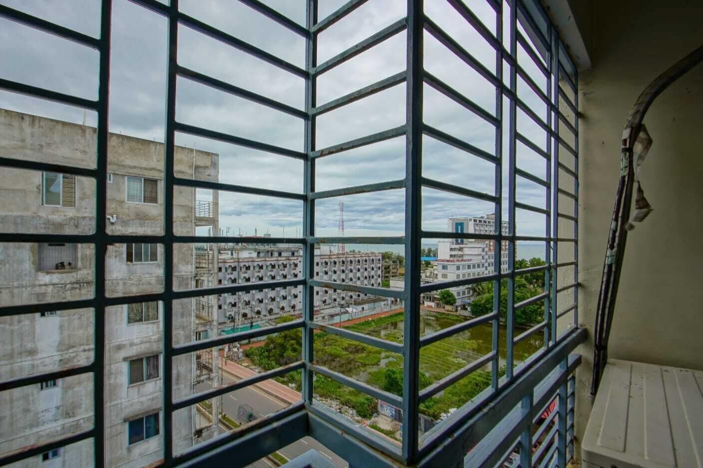 A view through a window with a grid pattern, overlooking a building complex with multiple floors and balconies.