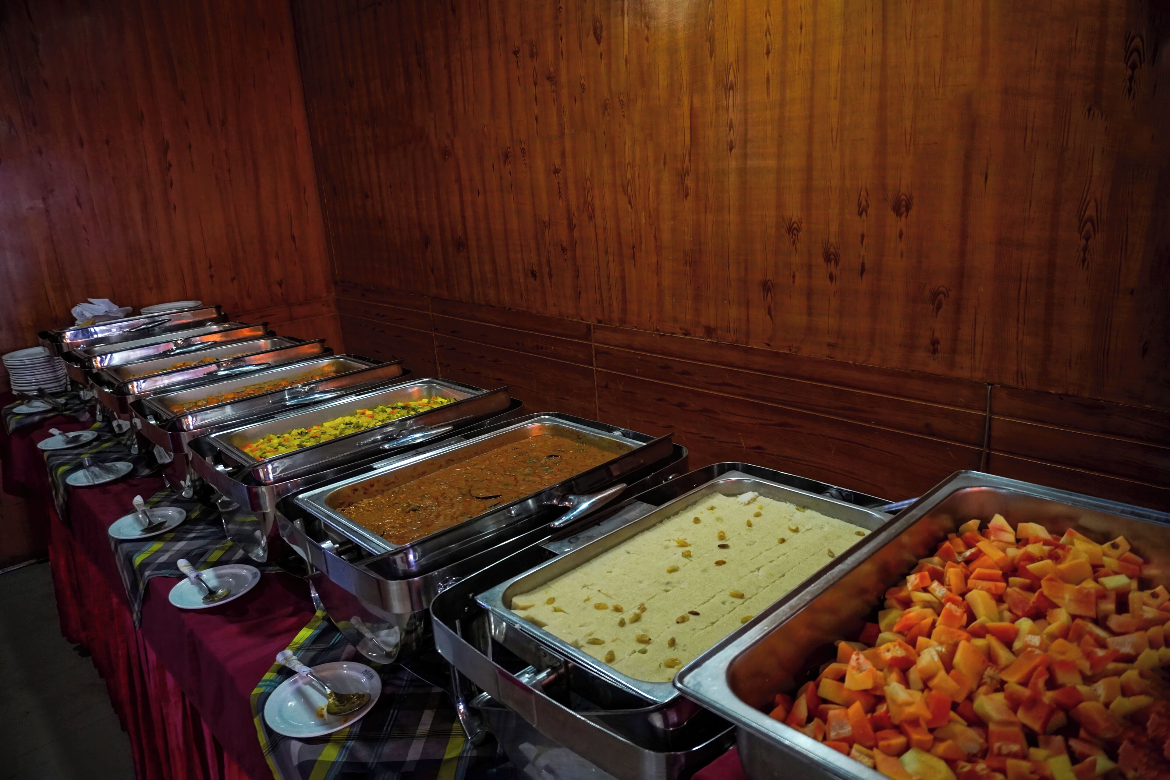 Un bufé con diversos alimentos presentados en bandejas metálicas.