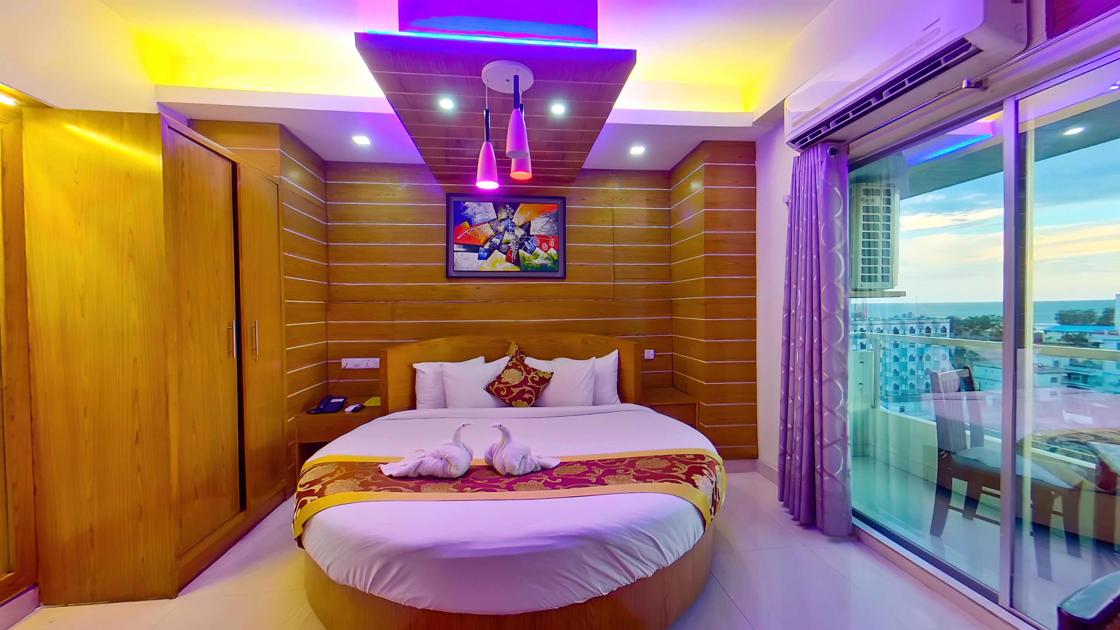 Una camera d'albergo con un letto grande, pareti in legno, un quadro sopra il letto e vista attraverso una grande finestra.