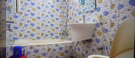 Un baño con lavamanos blanco, inodoro y ducha. Las paredes están revestidas con un diseño de piedrecita.