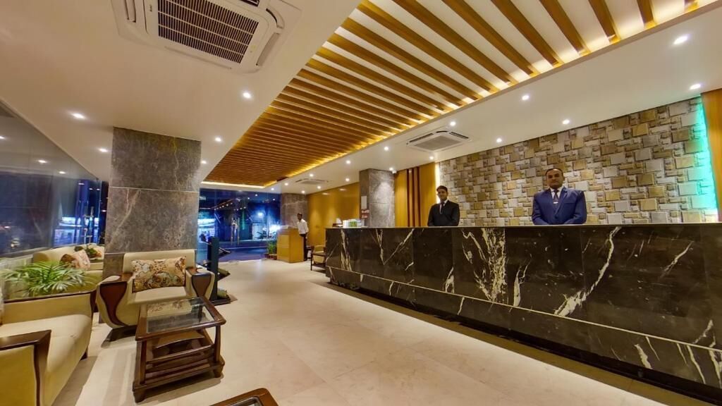 A hotel lobby with a reception desk, seating area, and a modern ceiling design.