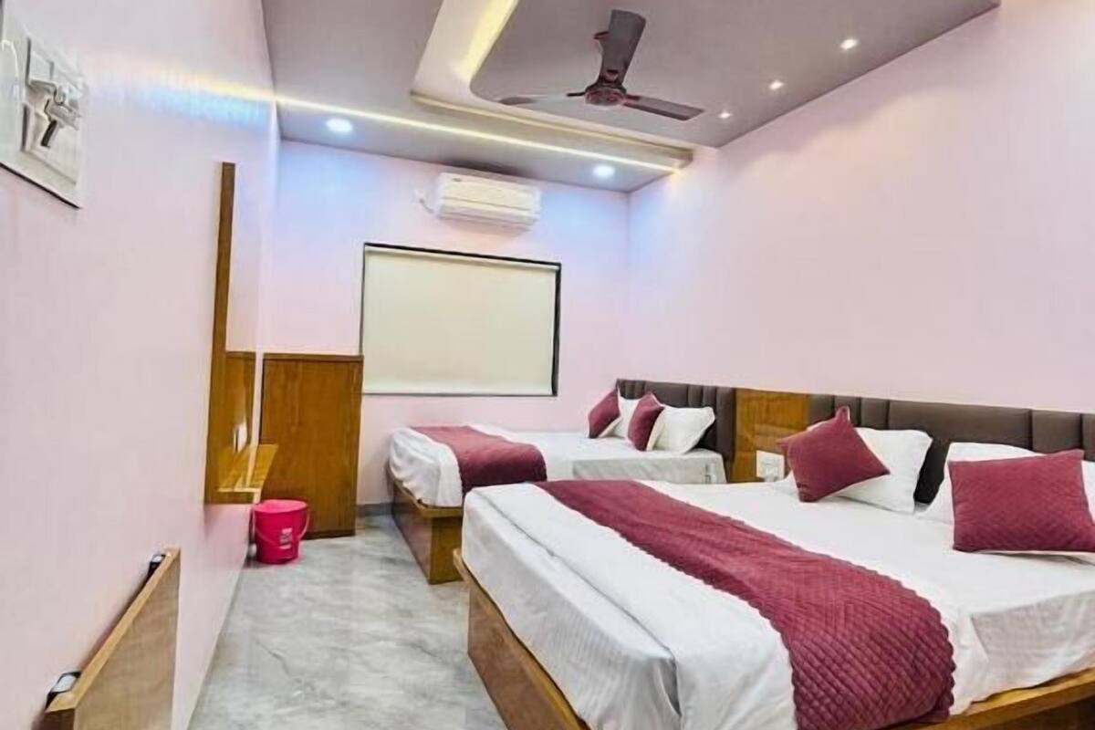A modern hotel room with a large bed, a smaller bed, a ceiling fan, and an air conditioning unit.