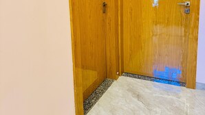 A wooden door with a metal handle and lock, leading to a room with a tiled floor and a pink wall. - SAIRAM RESIDENCY (Khuldabad)