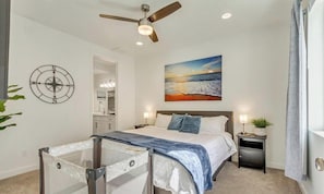 A bedroom with a bed, nightstands, a ceiling fan, a painting, and a compass wall decoration.