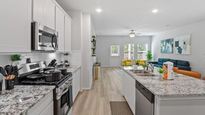 Une cuisine moderne avec des meubles blancs, une cuisinière en acier inoxydable et un plan de travail en marbre.