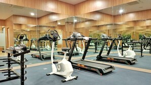 A gym with mirrored walls, treadmills, and weight machines. - Cordia Hotel Yogyakarta  (Temon)