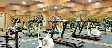 A gym with mirrored walls, treadmills, and weight machines.