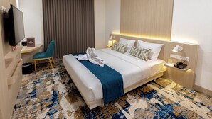 A hotel room with a bed, a desk with a flat-screen TV, a chair, a desk lamp, and a telephone. - Cordia Hotel Yogyakarta  (Temon)