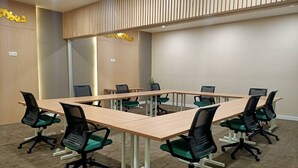 A conference room with a large rectangular table surrounded by eight black chairs with green seats. - Cordia Hotel Yogyakarta  (Temon)