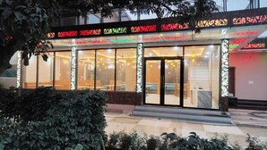 Un hôtel doté d’une façade en verre, d’une entrée couverte et d’un intérieur bien éclairé.