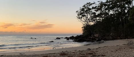 A beach with a rocky shoreline and trees in the background.