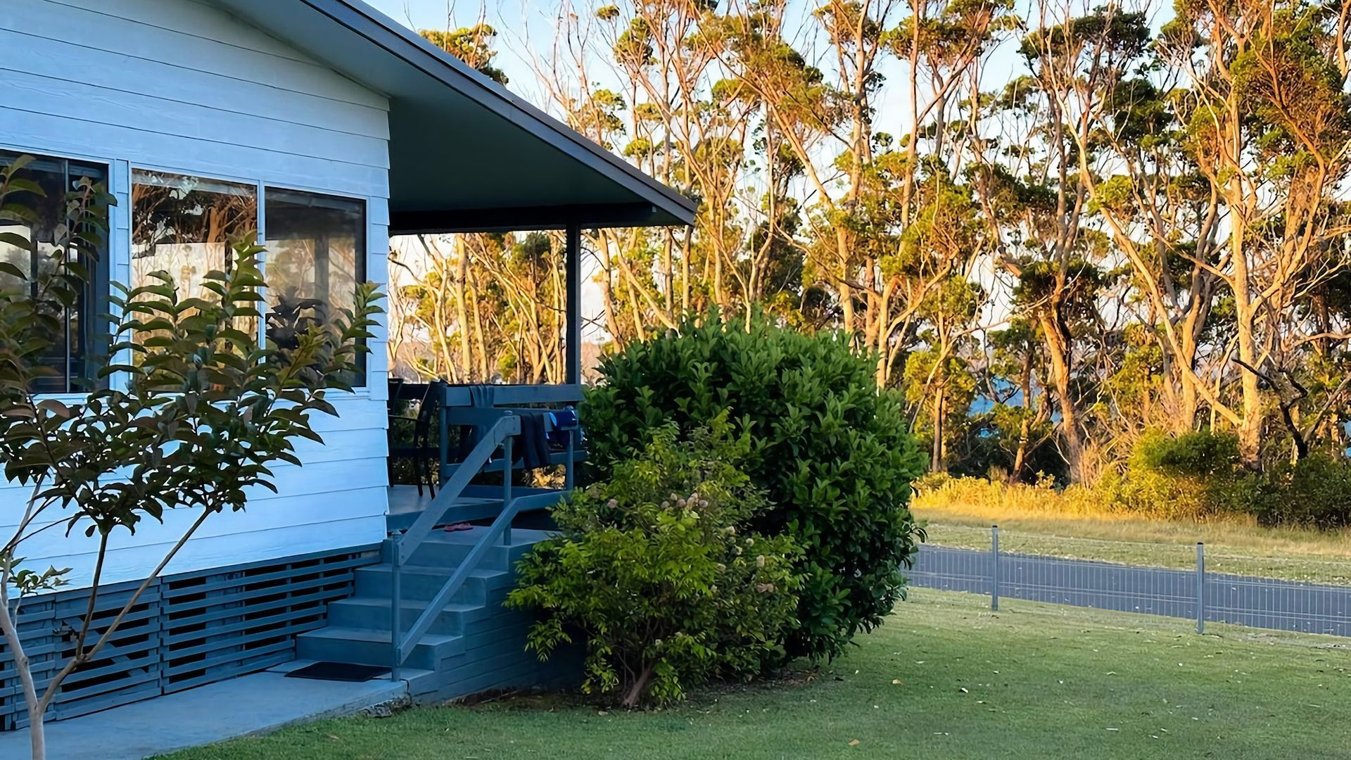 A modern house with a covered porch, a staircase leading to the entrance, and a well-maintained lawn.