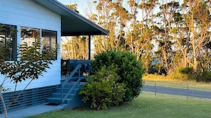 A modern house with a covered porch, a staircase leading to the entrance, and a well-maintained lawn.