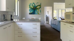 A modern kitchen with white cabinetry, a coffee maker, and a microwave. - Yonder is near the ocean and beach (Bendalong)