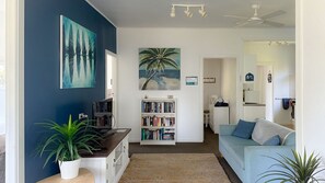 A living room with a bookshelf, a sofa, a coffee table, and a ceiling fan.